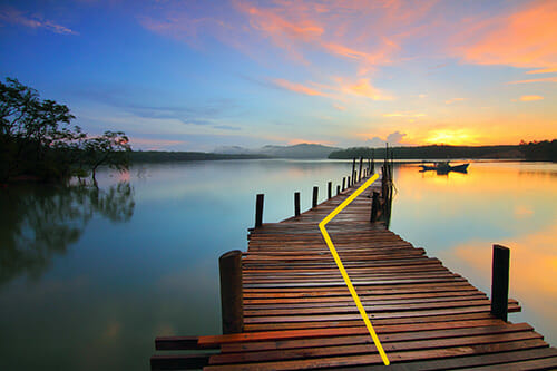 a jetty leading out to a lake at sunset