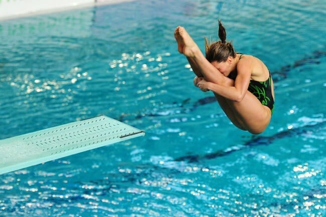 woman doing a spinning dive into a swimming pool