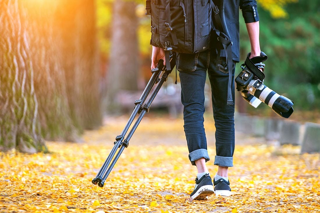 professional photographer with camera and tripod in autumn.