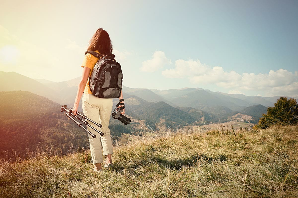 Professional,Photographer,With,Modern,Camera,And,Tripod,In,Mountains,,Back