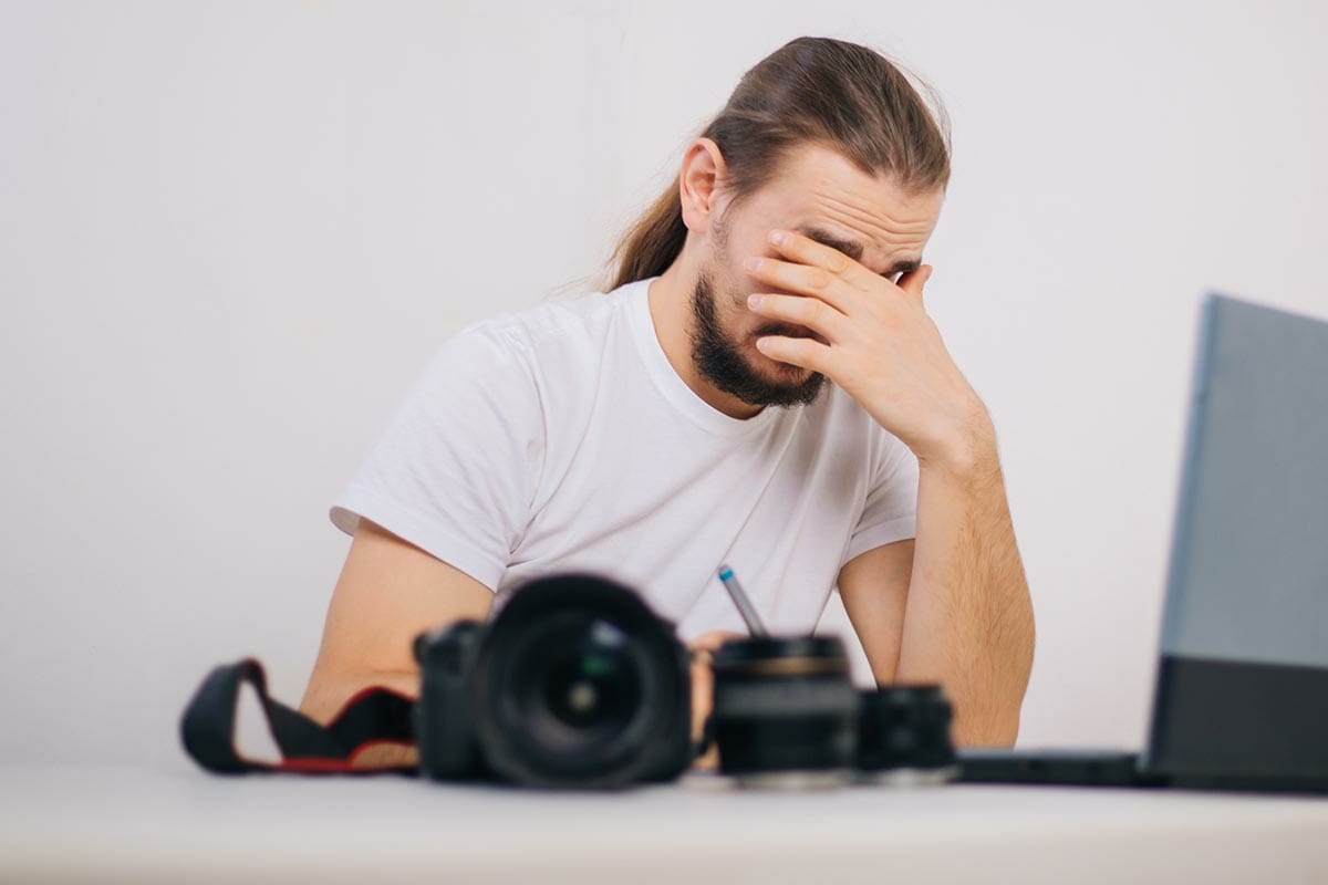 A,Photographer,Is,Thinking,In,Front,Of,A,Laptop,,Side