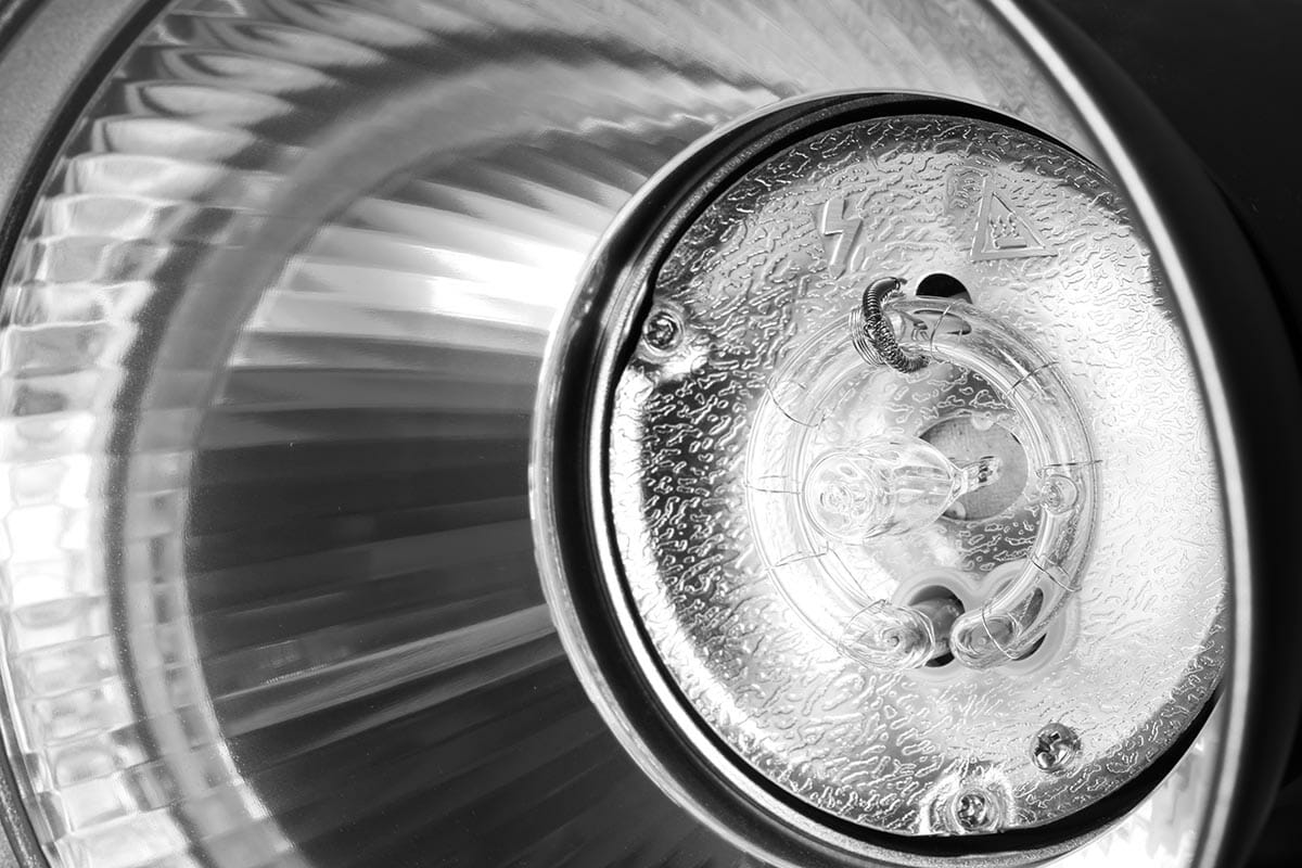 Reflector, pilot light bulb and round flash bulb of an studio flash head close-up. Monochrome image