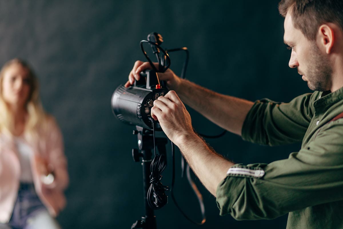 young handsome man working with a professional studio strobe photo flash light.close up photo. blurred background