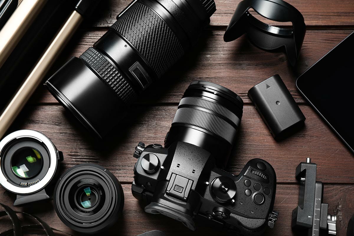 Flat lay composition with camera and video production equipment on brown wooden background