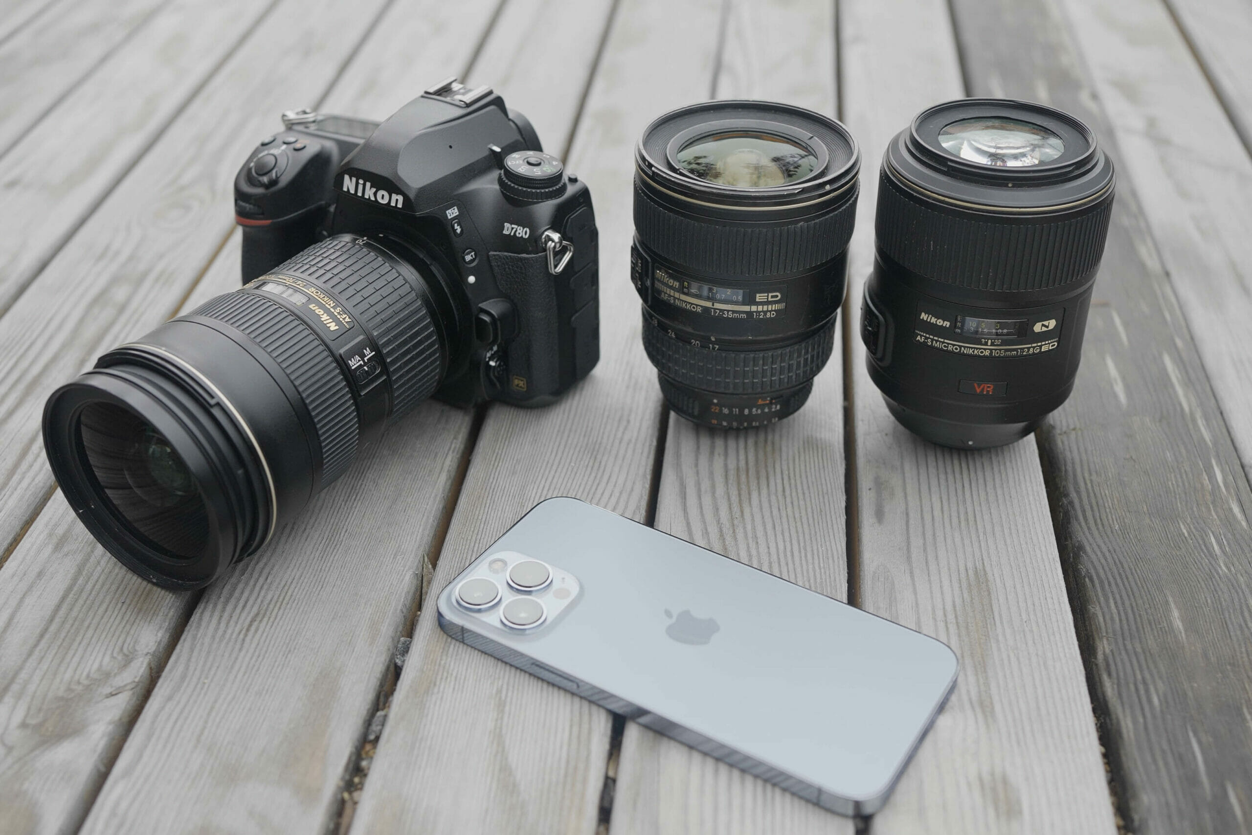 Moscow - Russia, 10.10.2021: new Nikon camera with lens and a modern Iphone 13 pro max lying outdoors on a wooden surface. Action. Professional equipment for shooting.