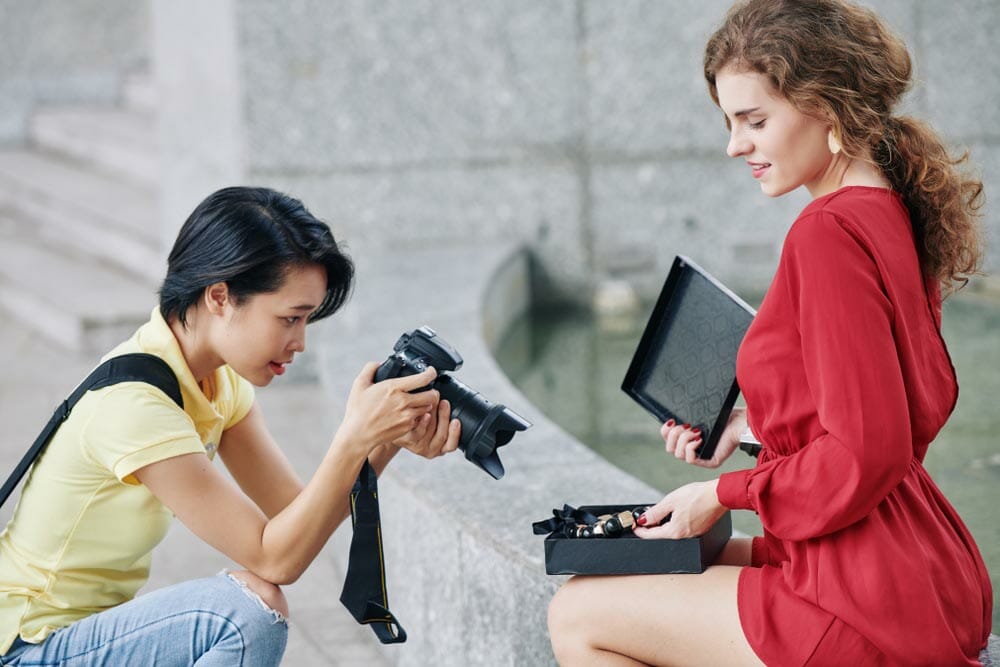 Pretty young woman opening jewelry box and showing massive necklace to photographer